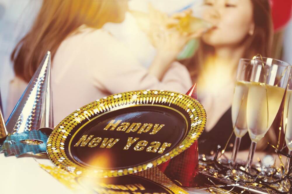 New Year celebration with Happy New Year plate, party hats, and champagne glasses.